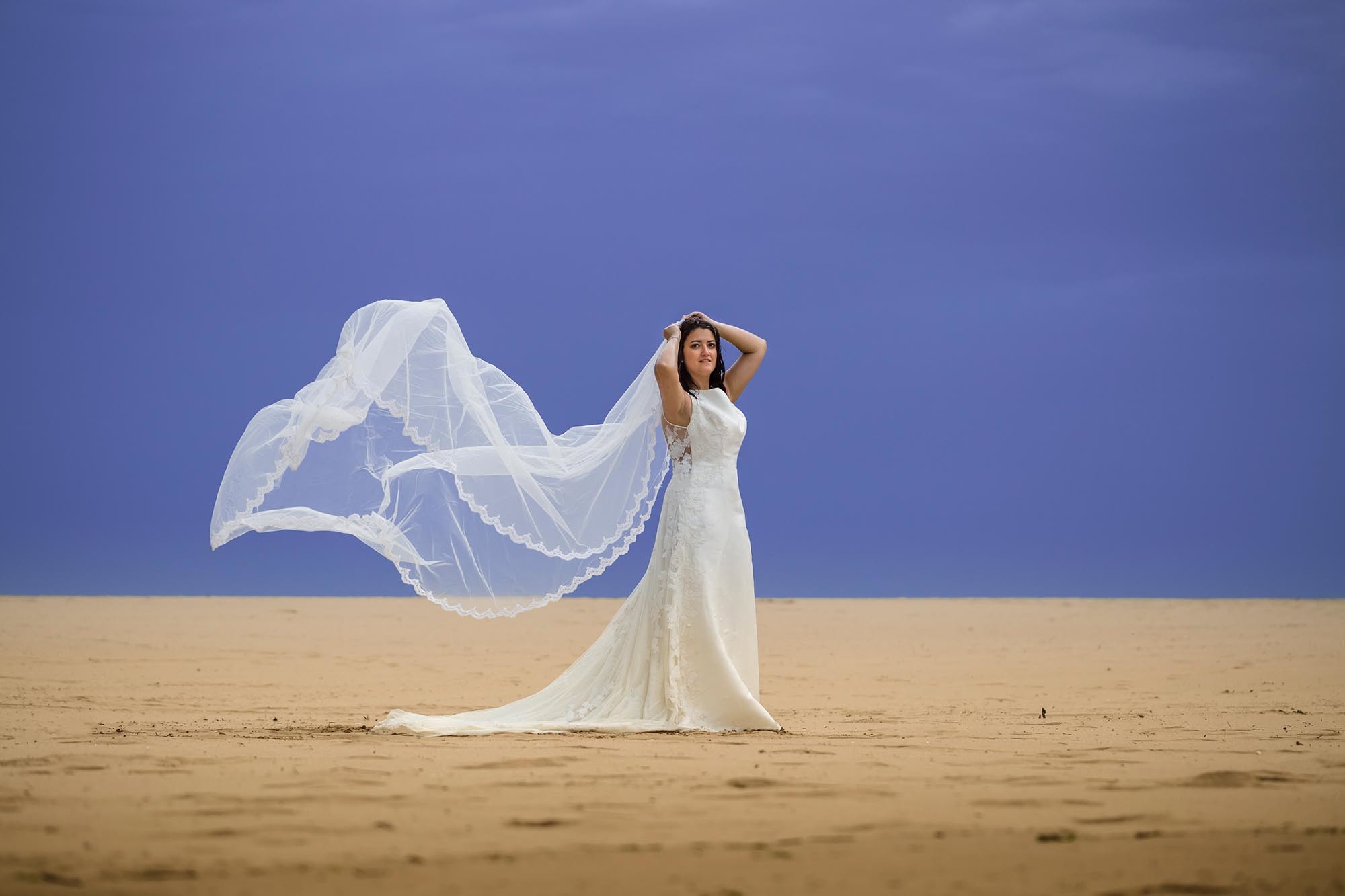novia con velo al aire en la playa