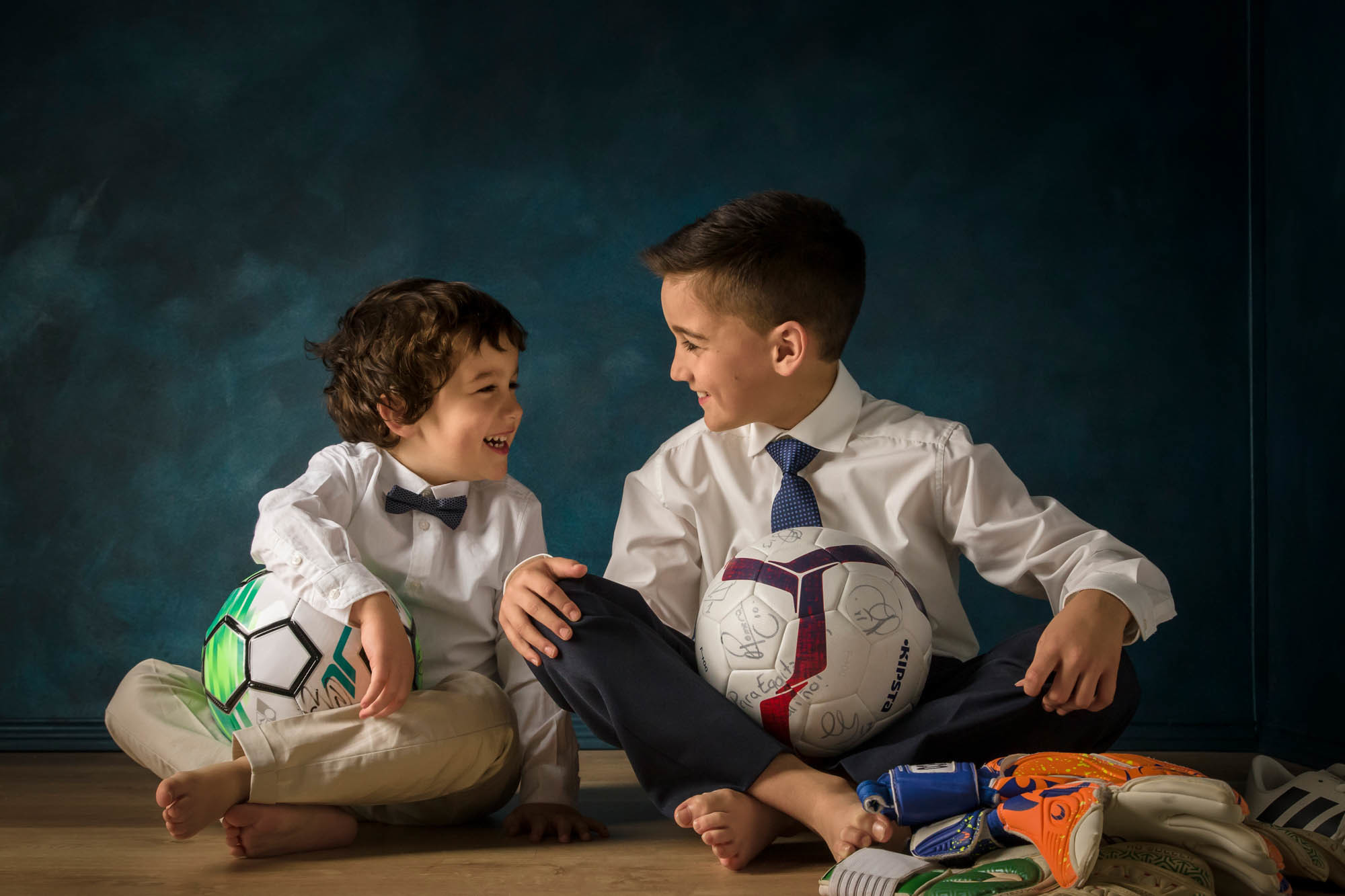 niño de comunion y hermano con guantes de futbo