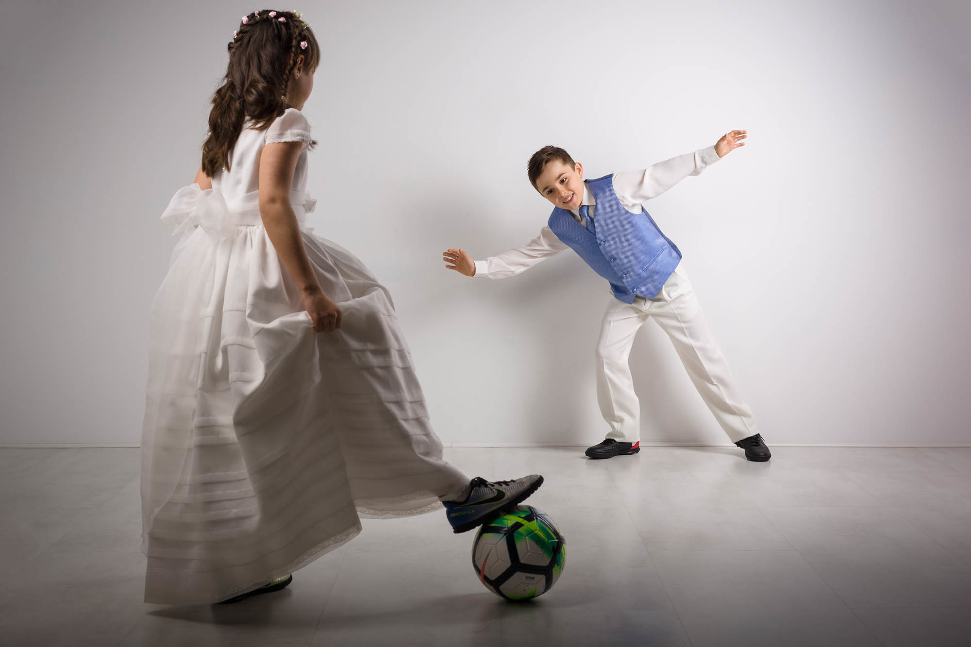 niño y niña de comunion jugando al futbol