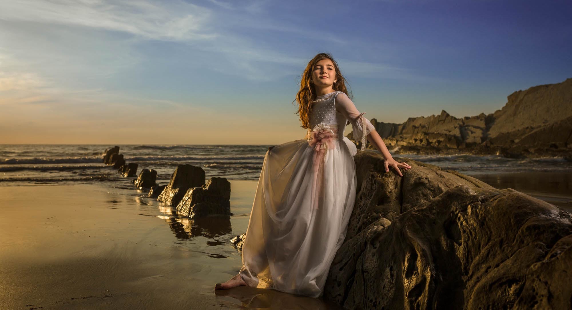 niña de comunion en la playa al atardecer