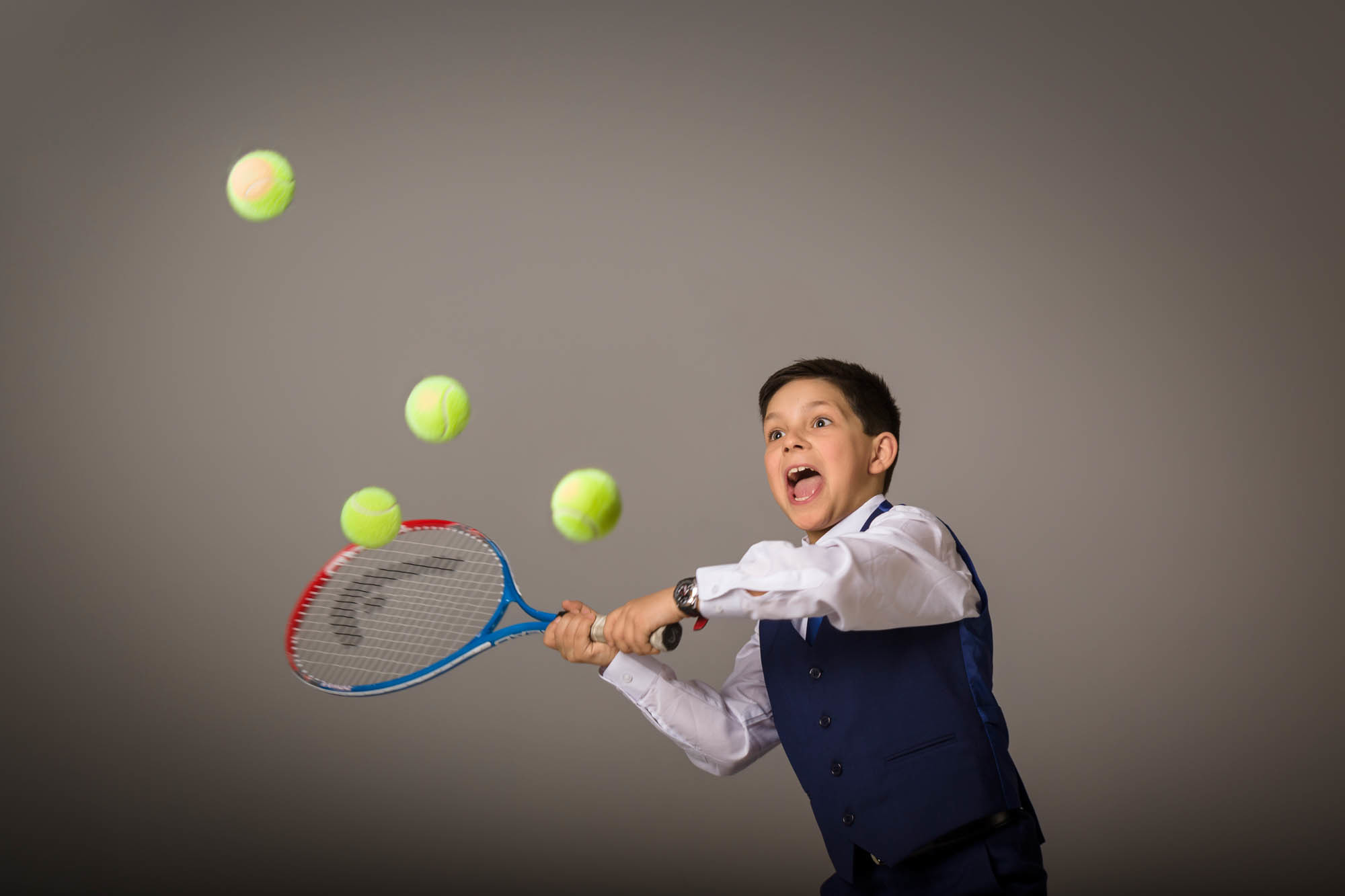 niño de comunion con raqueta y pelotas de tenis